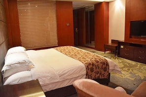 A hotel room with a bed, a desk, a chair, a television, and a wardrobe. - Wanfu International Hotel (Xianyang)