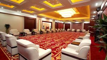 A conference room with a long table and rows of chairs, a red carpet, and a modern ceiling design.