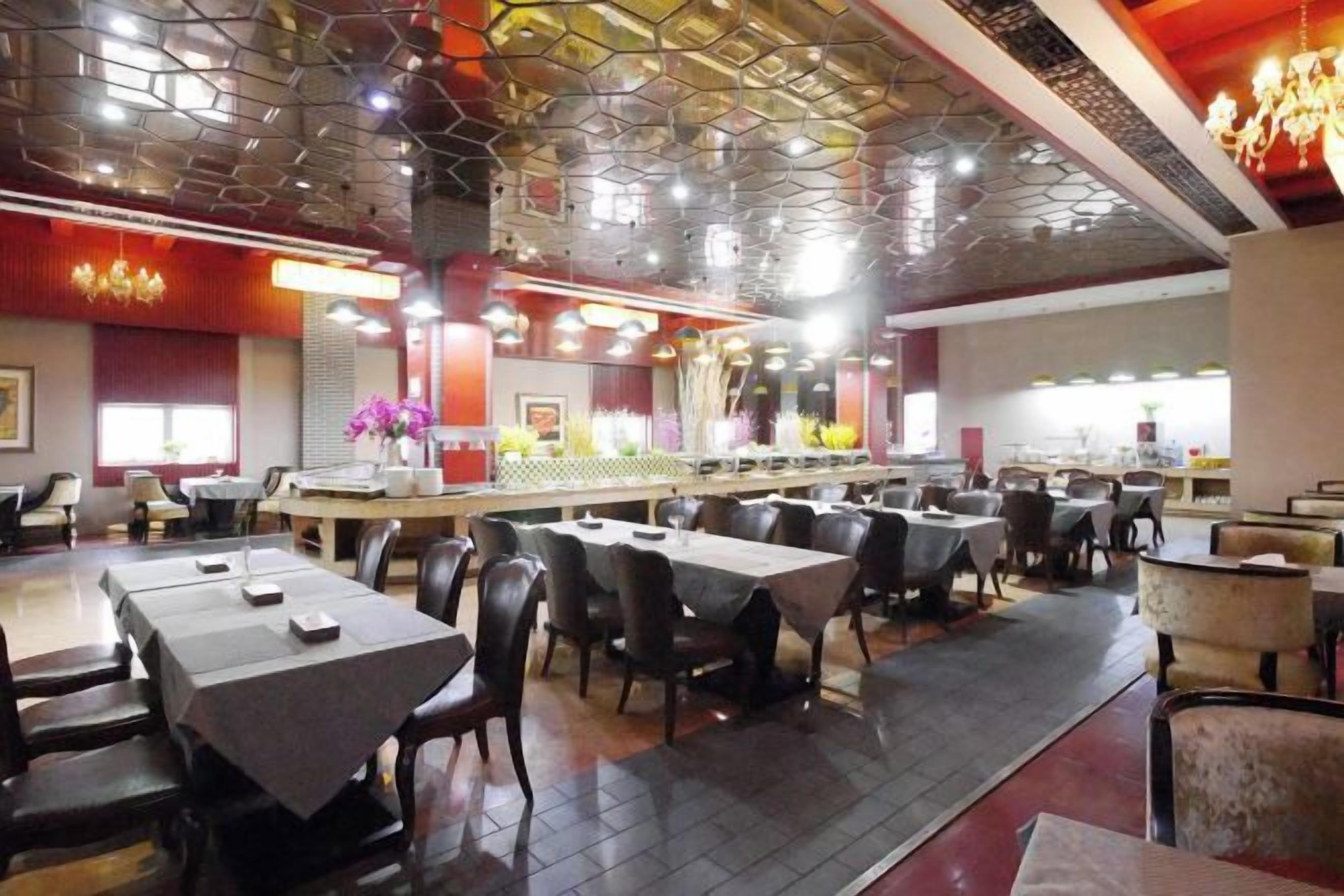 A restaurant with multiple tables and chairs, a bar area, and a decorative ceiling.