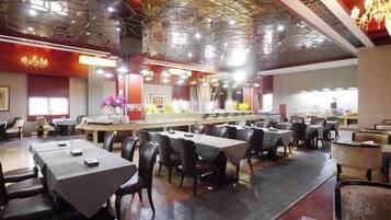 A restaurant with multiple tables and chairs, a bar area, and a decorative ceiling.