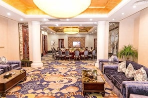 A hotel lobby with a large dining table, sofas, and a carpeted floor. - Wanfu International Hotel (Xianyang)