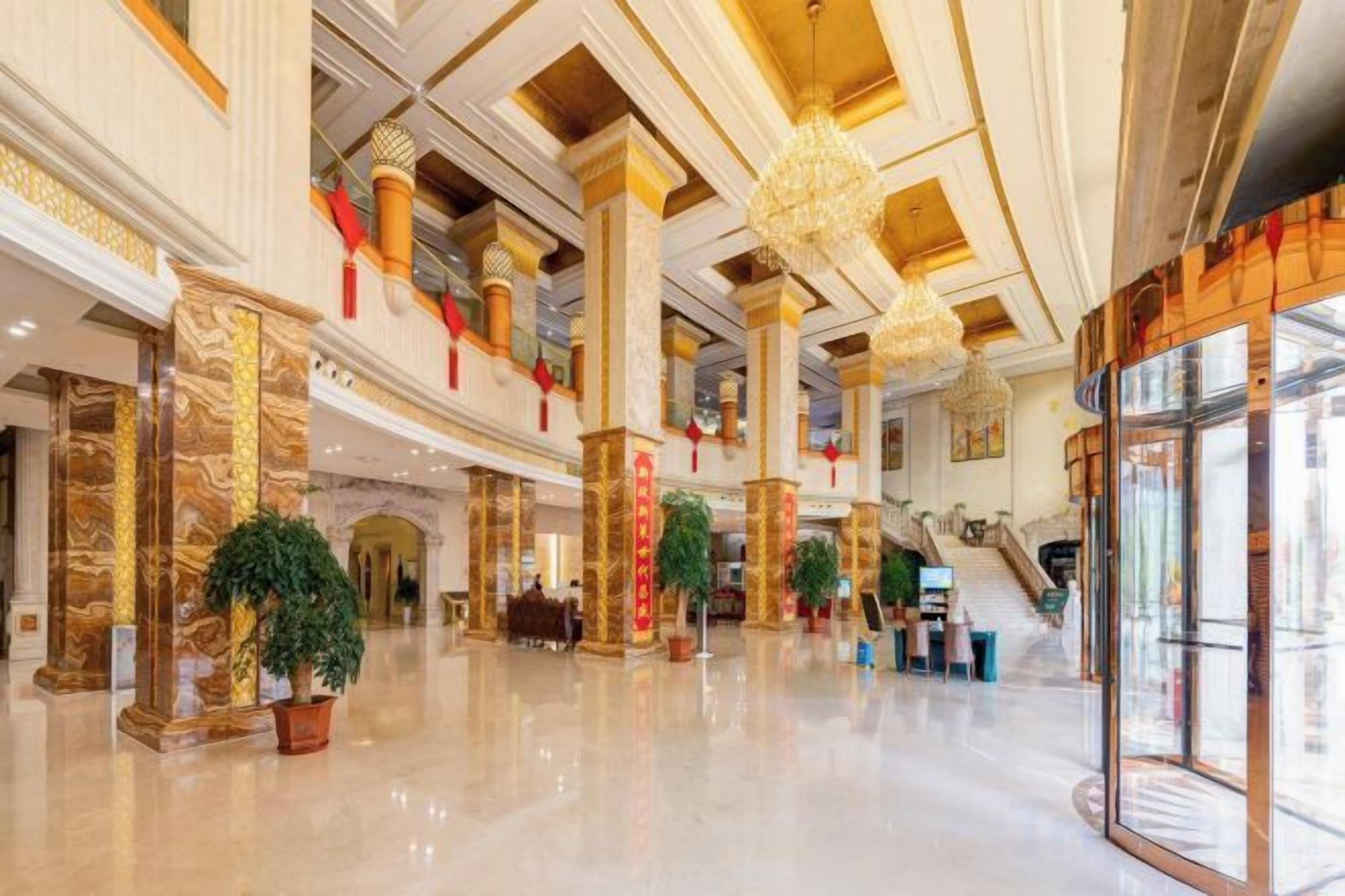 A spacious lobby with high ceilings, marble columns, and a central staircase.