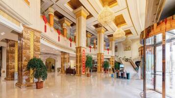 A spacious lobby with high ceilings, marble columns, and a central staircase.
