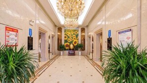 A hotel lobby with a chandelier, a sunflower mural, and potted plants. - Wanfu International Hotel (Xianyang)