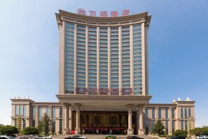 A tall hotel with a modern facade, featuring a prominent entrance with columns and a large sign above. - Wanfu International Hotel (Xianyang)