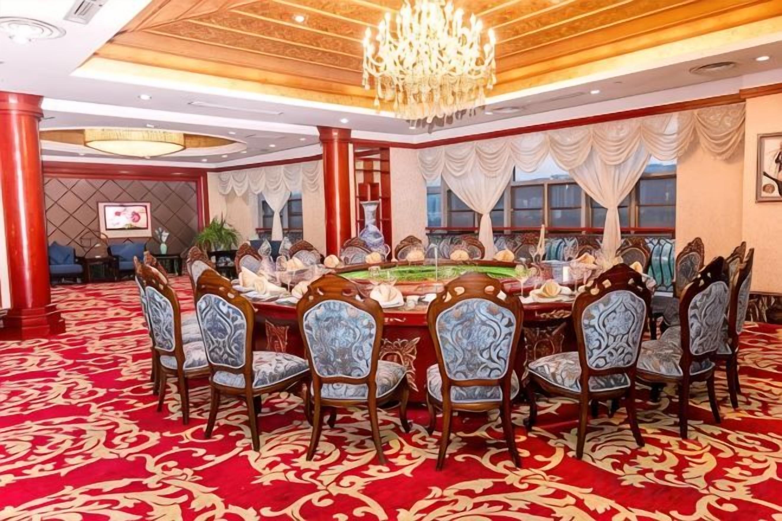 Une salle de conférence avec une table ronde, des chaises et un lustre.