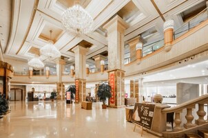 Un vestíbulo amplio con techos altos, candelabros y una imponente escalera.