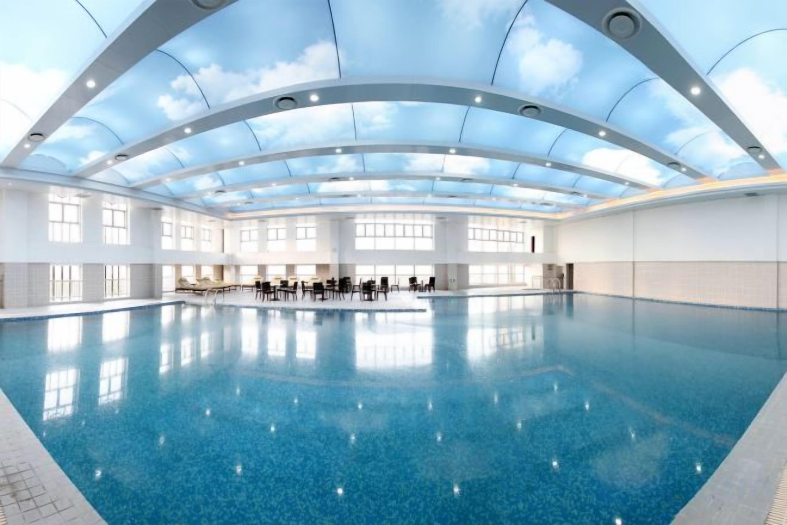 A large indoor swimming pool with a high ceiling and skylights.