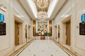 A hotel corridor with a chandelier, floral wall mural, and a reception desk. - Wanfu International Hotel (Xianyang)