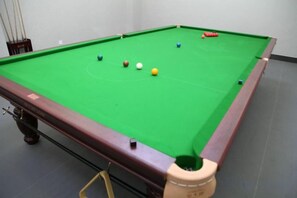 Una mesa de billar con bolas en juego, una vara y un tapete.