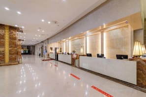 A hotel reception area with a long reception desk, multiple computer stations, and a marble floor. - Wanfu International Hotel (Xianyang)