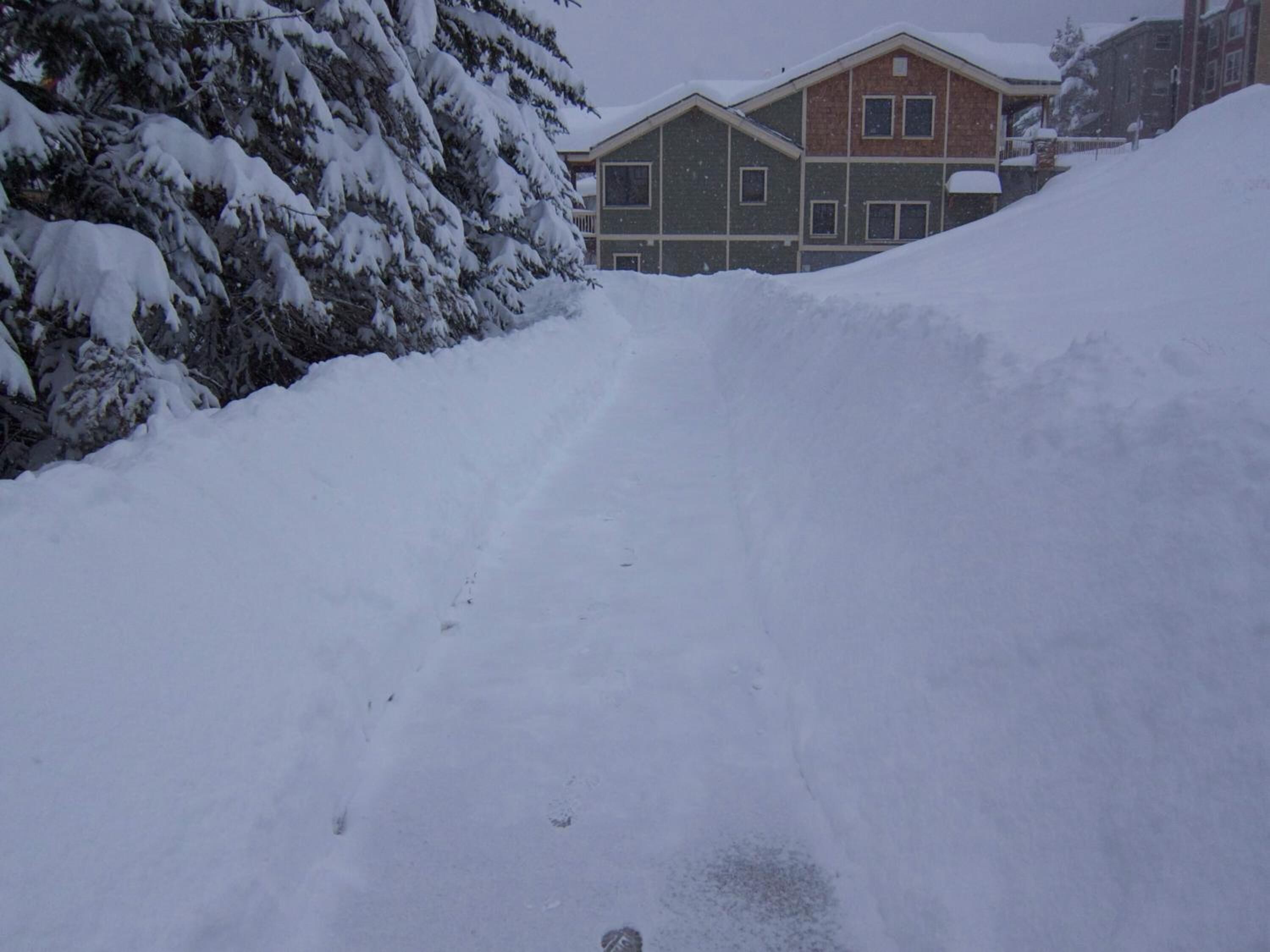 A snow-covered road with a building in the background.