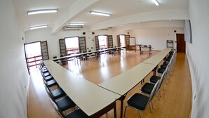 Un salón de conferencias con una larga mesa y sillas, ventanas amplias y un techo alto.
