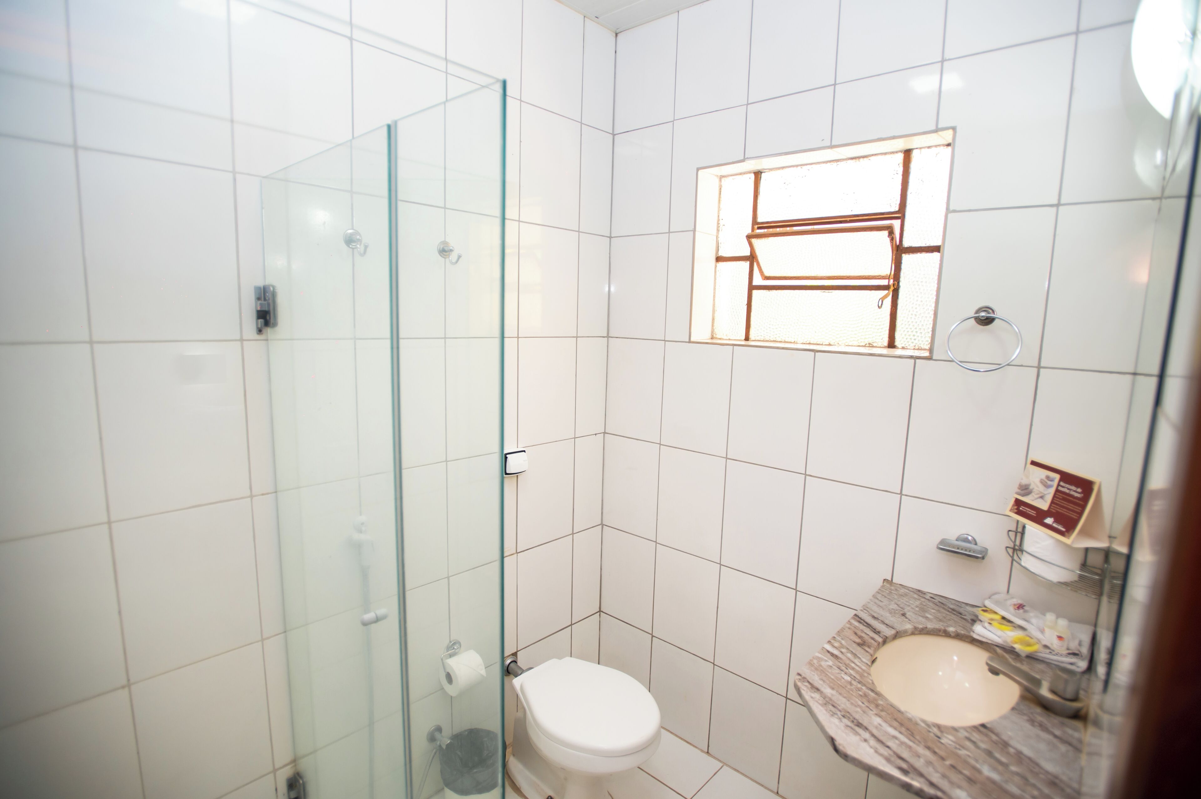 Un baño con cabina de ducha de vidrio, inodoro y lavamanos con encimera de mármol.