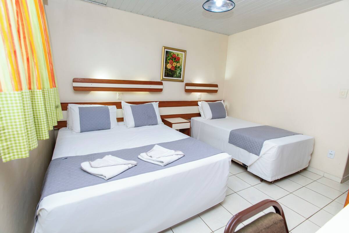 A hotel room with two beds, a wooden headboard, a painting on the wall, and a chair.