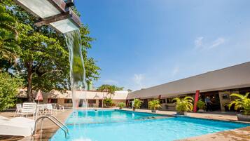Una piscina al aire libre, sillones reclinables de piscina
