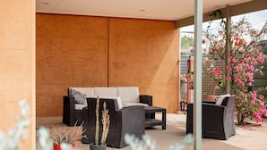 An outdoor seating area with wicker furniture and a potted plant. - Mud Hut Motel (Coober Pedy)