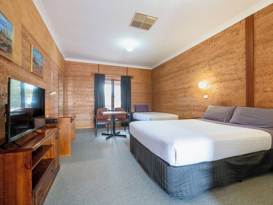 A hotel room with a bed, a TV, a desk, and a chair.