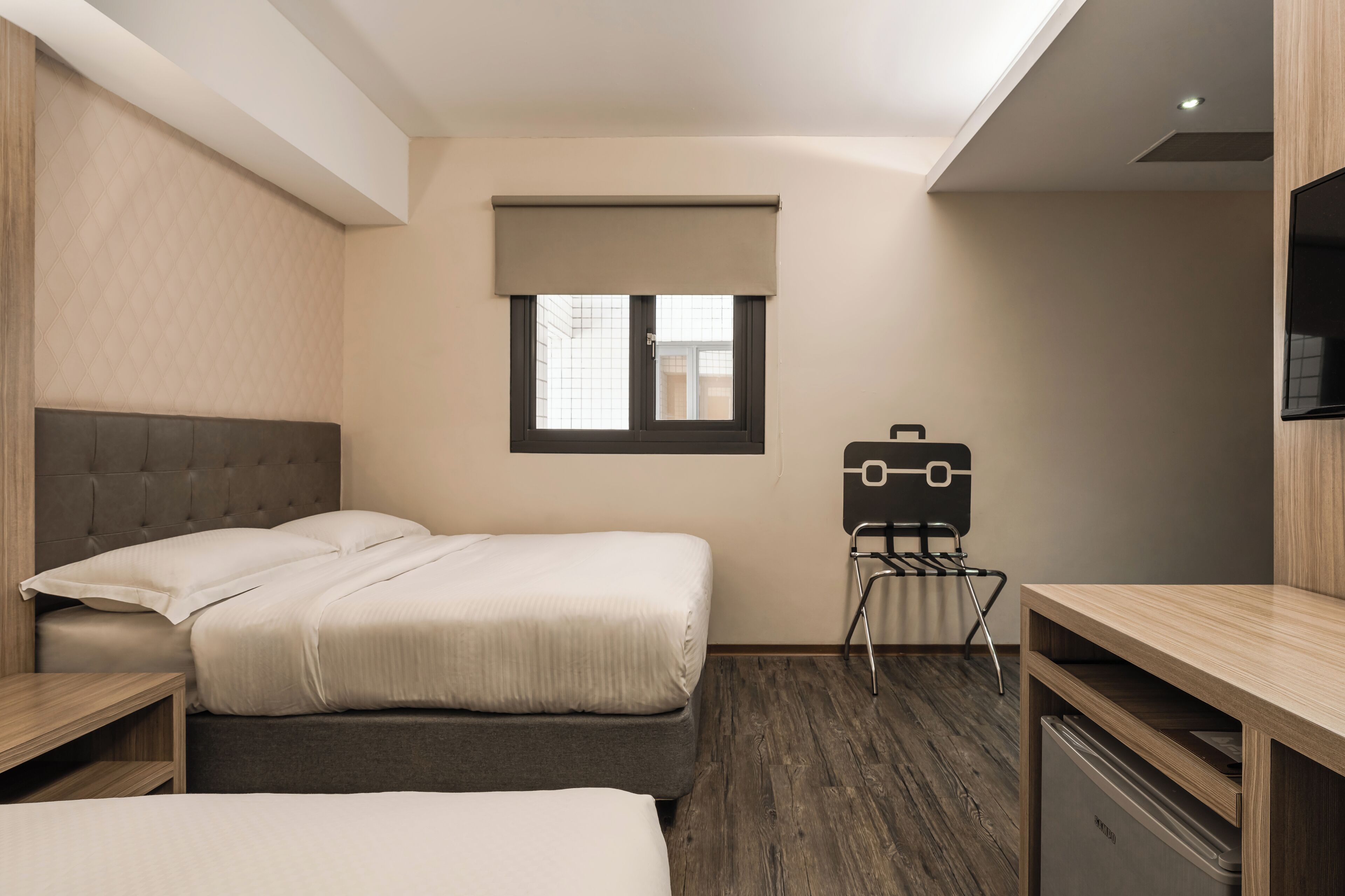 A modern hotel room with a bed, a desk, and a chair.