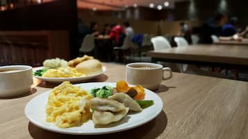 A dining table with plates of food and coffee cups.