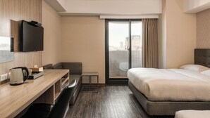 Ein modernes Hotelzimmer mit Schreibtisch aus Holz, einem Flachbildfernseher, einem Bett und Blick auf die Stadt durch das Fenster.