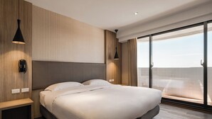 Ein modernes Schlafzimmer mit einem großen Bett, Holzwandverkleidung und Blick durch raumhohe Fenster.