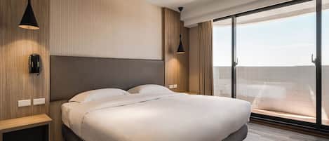 Un dormitorio moderno con una cama grande, paneles de madera y vistas a través de ventanas de gran altura.