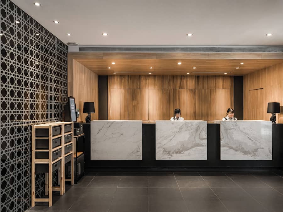 A reception area with three marble counters, wooden paneling, and a lattice wall.