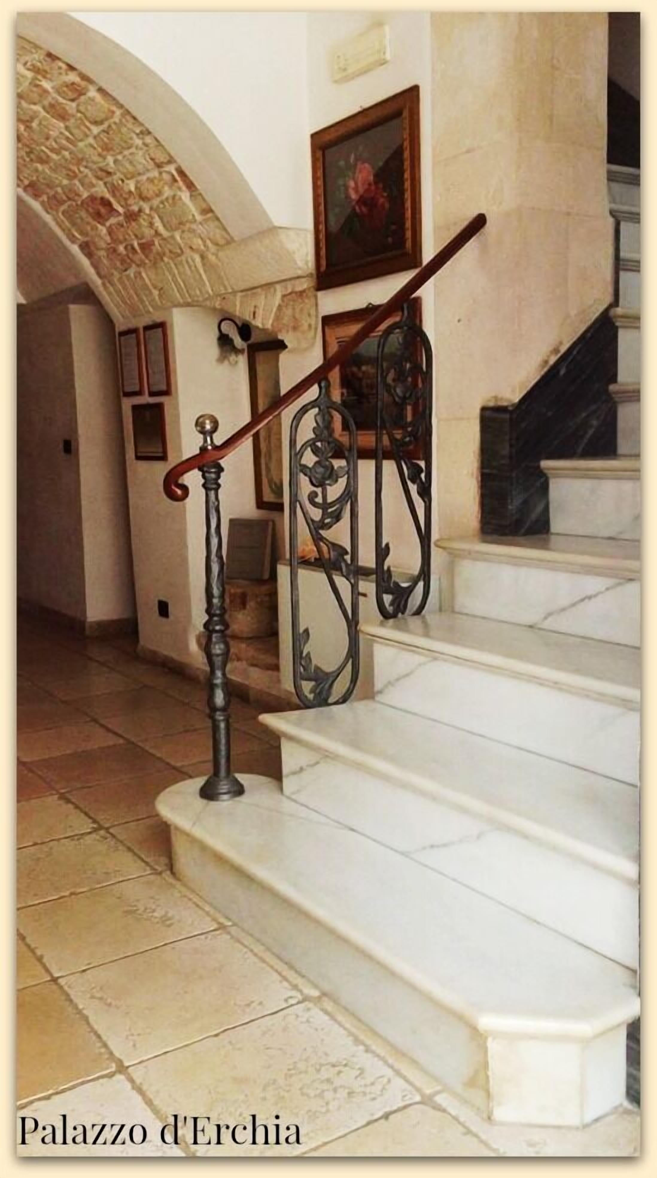 A staircase with a wrought iron railing and a stone wall.