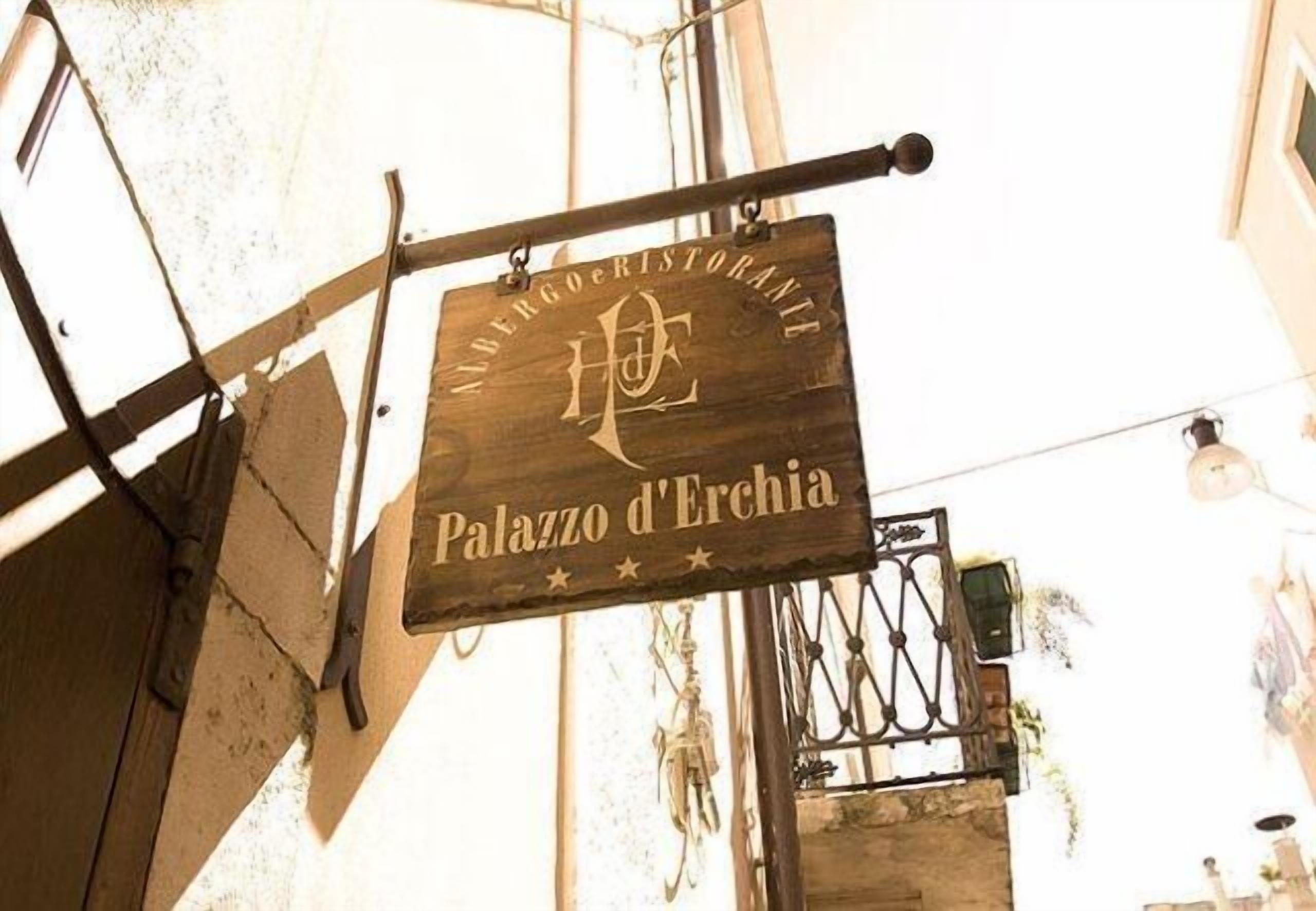 Une enseigne en bois portant l’inscription « Palazzo d’Erchia » et un logo, suspendue à un support métallique.