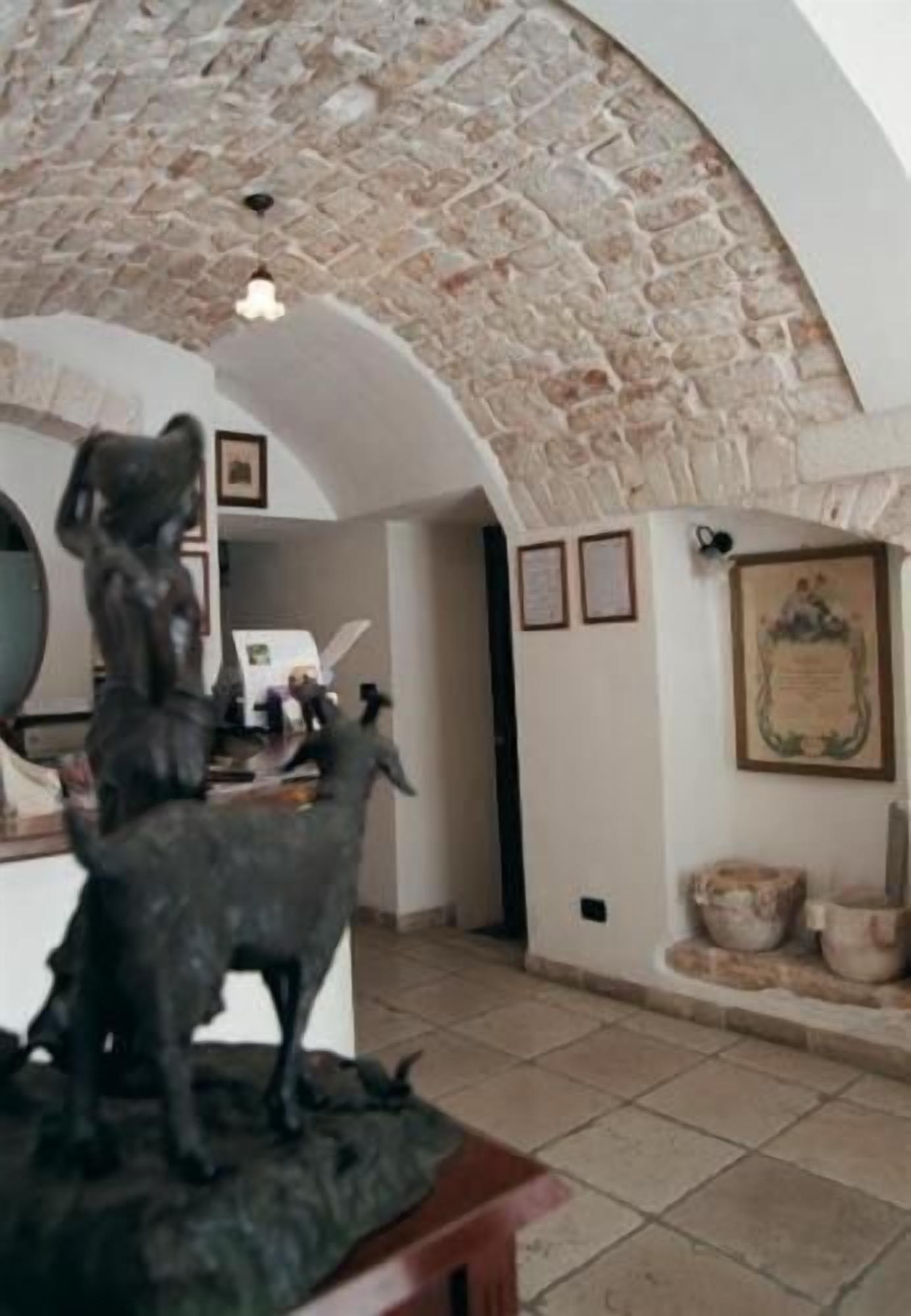 Una habitación con techo de piedra, una estatua de un perro, un certificado enmarcado y suelo de baldosas.