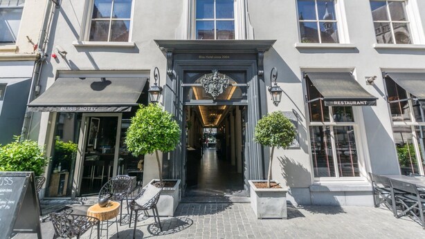 A hotel with a classic facade, a sign indicating it has been in operation since 2004, and outdoor seating with tables and chairs. - Bliss Boutique Hotel (Breda)
