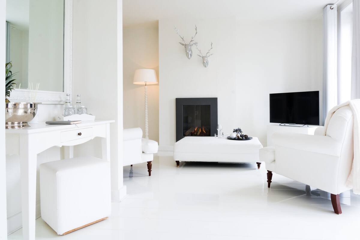 Ein modernes, weißes Wohnzimmer mit Kamin, Fernseher und einem weißen Sofa.