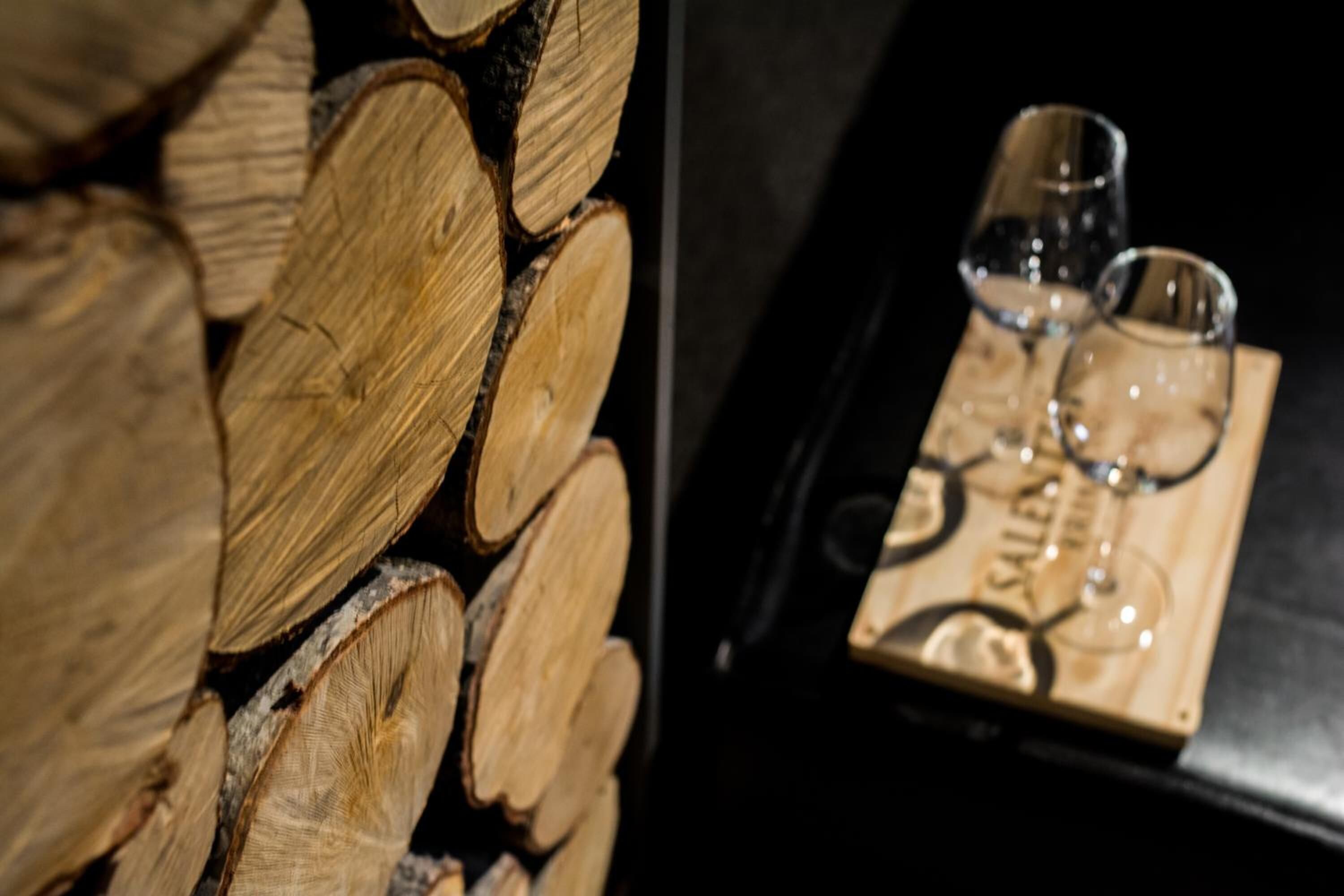 A stack of firewood and a tray with two glasses and a bottle.