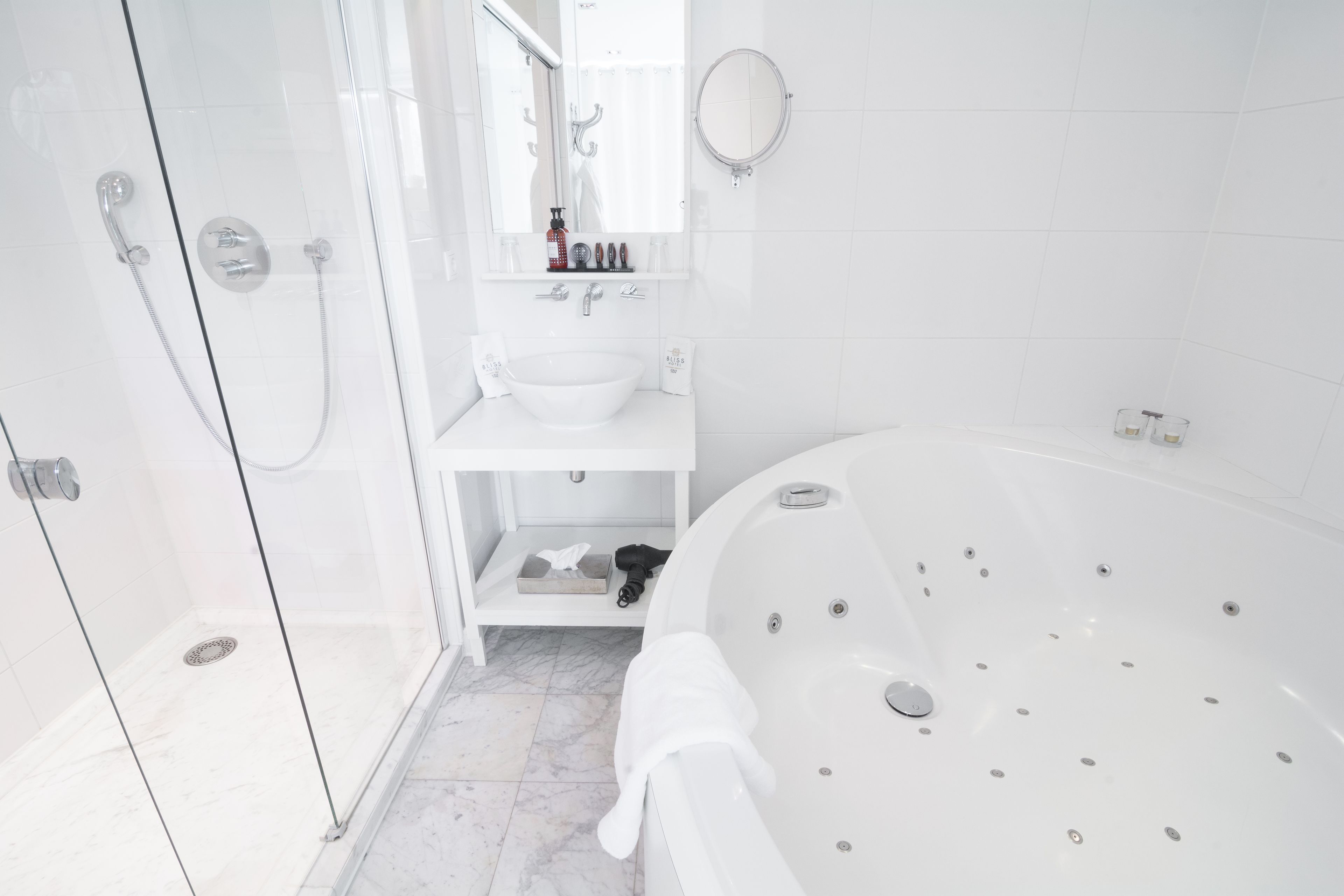 Un baño moderno con ducha de vidrio, lavabo blanco, bañera grande y espejo sobre el lavabo.
