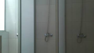 Box de chuveiro com porta de vidro, chuveiro manual e chuveiro fixo na parede.