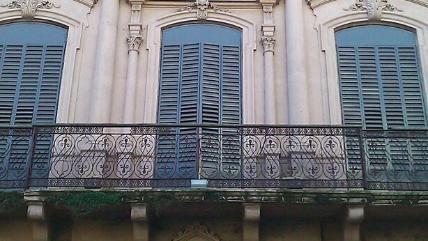 A building facade with three arched windows and decorative iron railings. - Montevideo Chic Boutique Hostel (Montevideo)