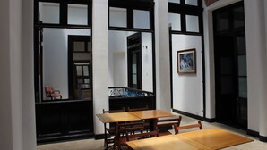A room with a wooden table and chairs, large windows with black frames, and a painting on the wall. - Montevideo Chic Boutique Hostel (Montevideo)
