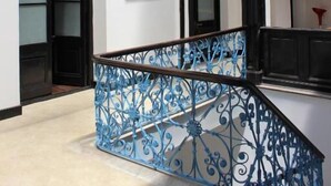 A spacious interior with a high ceiling, a staircase with blue wrought iron railings, and large black-framed windows. - Montevideo Chic Boutique Hostel (Montevideo)
