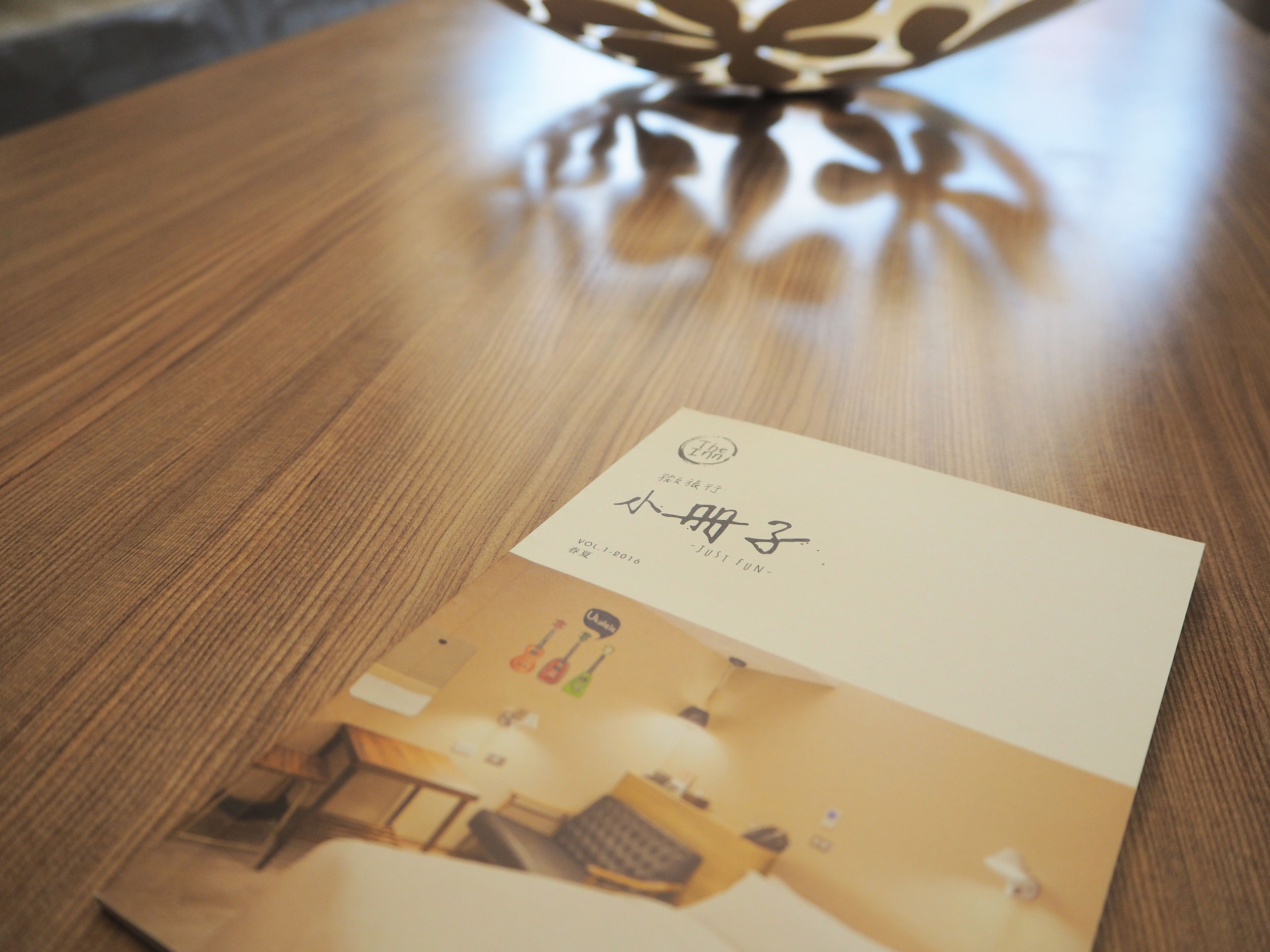 Una mesa de madera con una tarjeta de presentación y una revista encima.