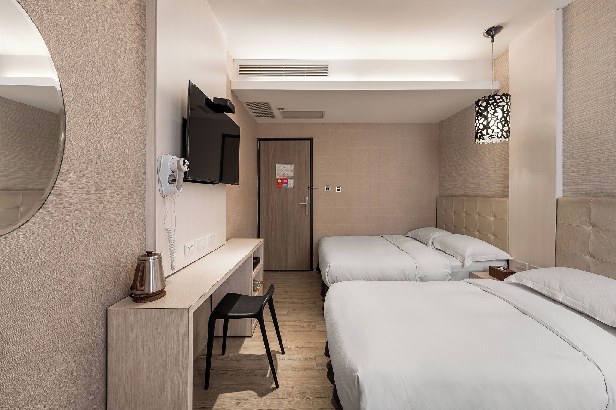 Quarto de hotel com cama, escrivaninha, cadeira, televisão e espelho.