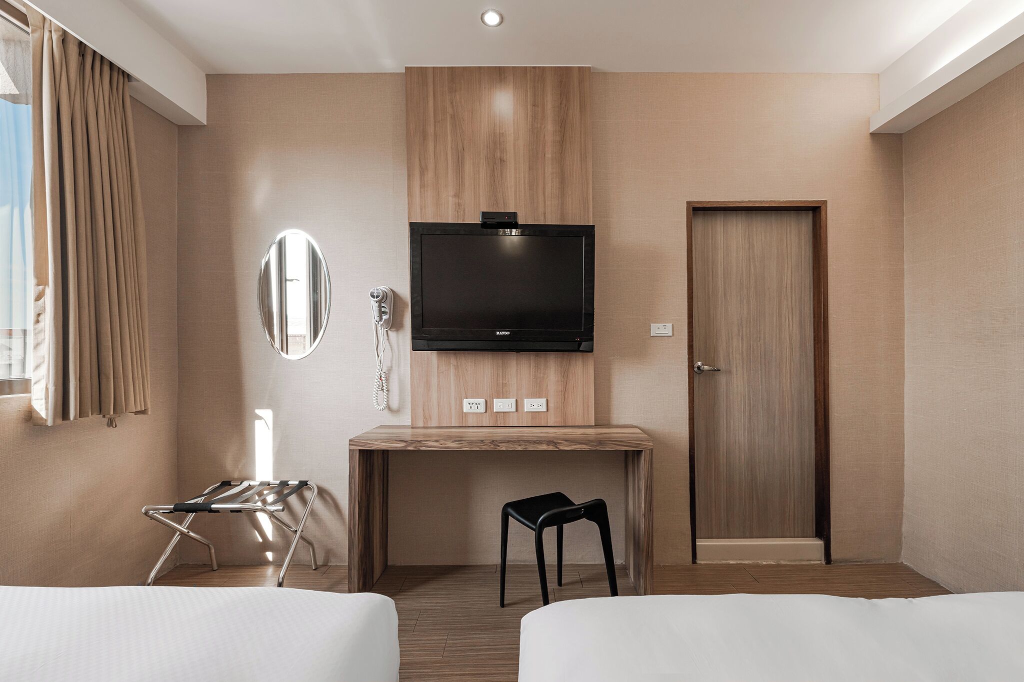 Una habitación de hotel con cama, escritorio, televisor, espejo y puerta.