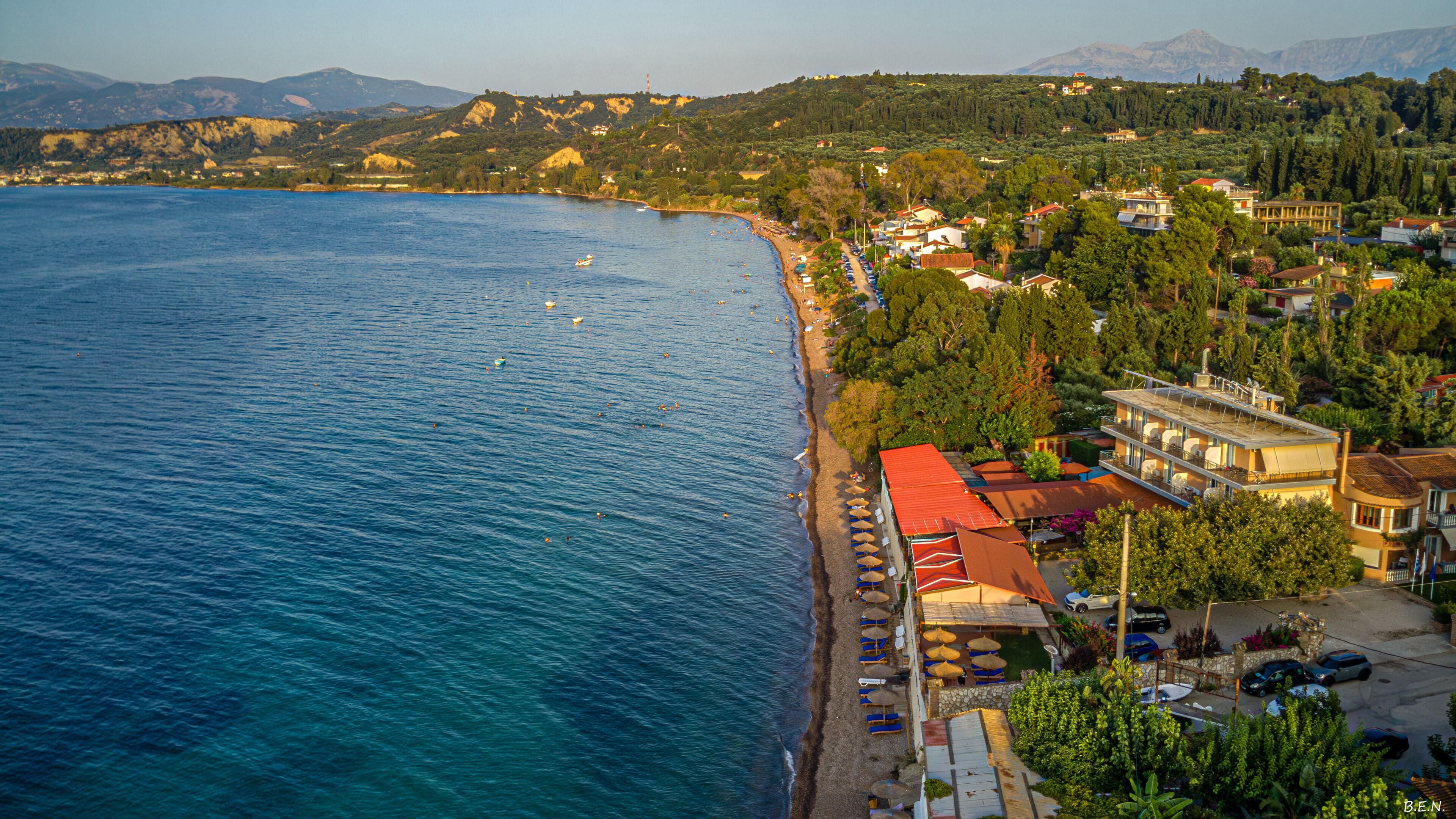 Uma cidade costeira com praia, edifícios e montanhas ao fundo.