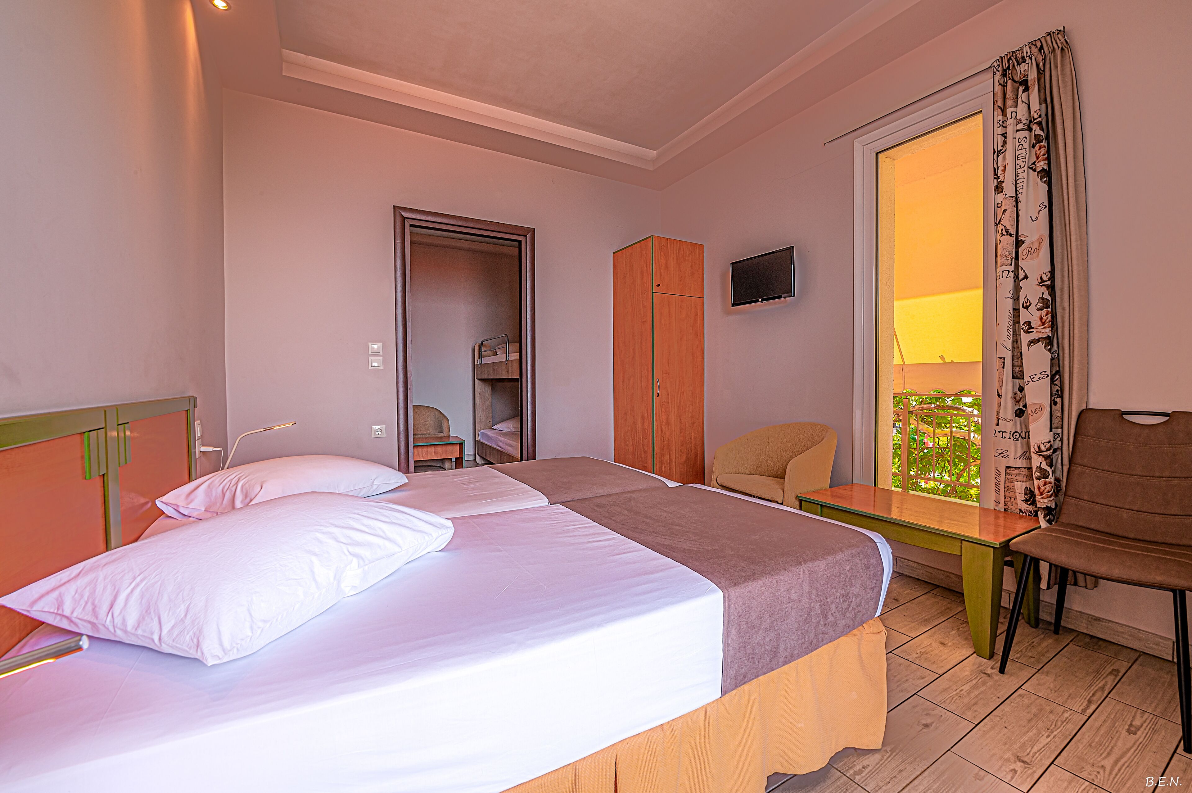 Una habitación de hotel con cama, una silla, una mesa, un armario y un televisor.