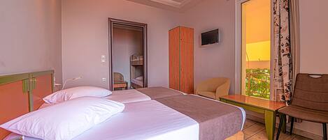 Una habitación de hotel con cama, una silla, una mesa, un armario y un televisor.