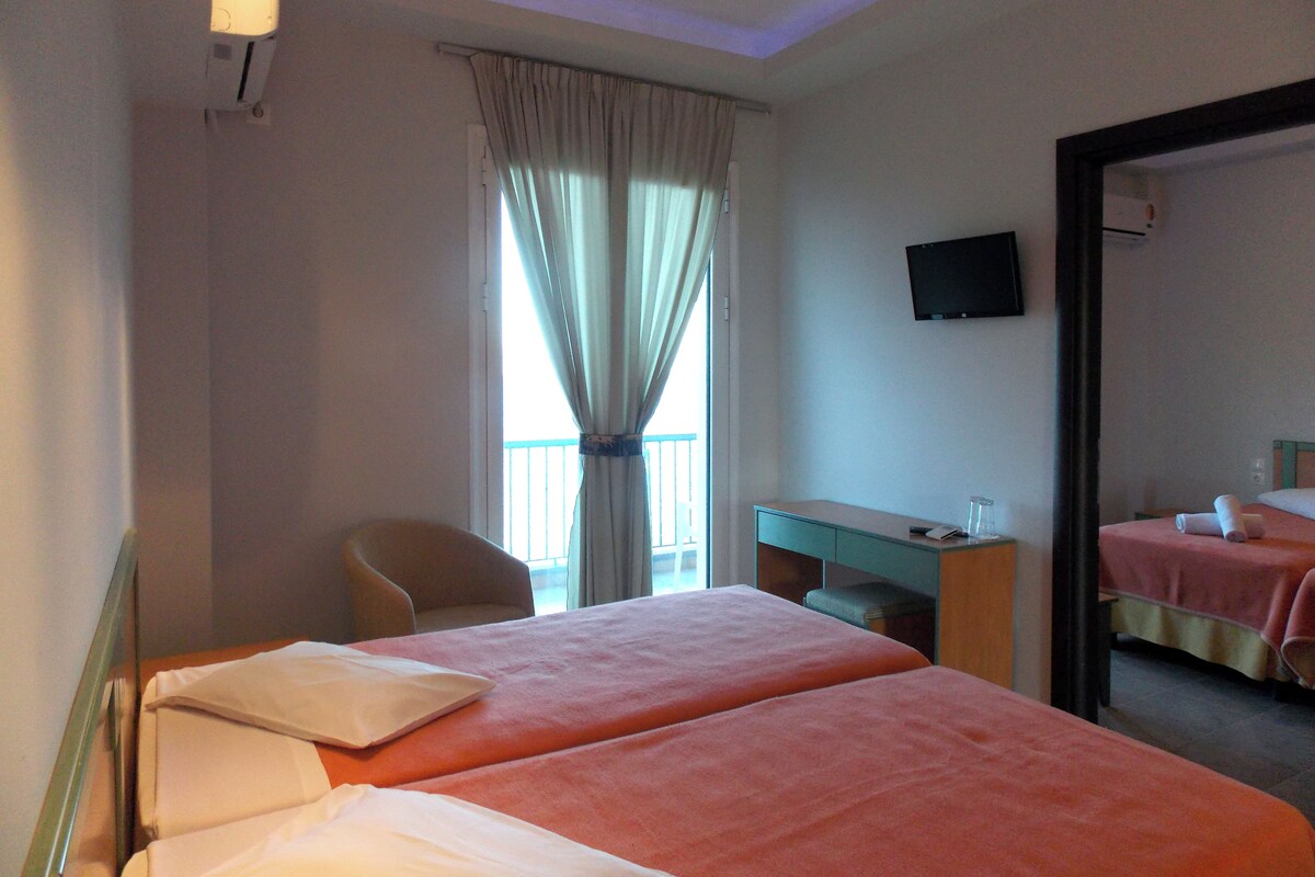 A hotel room with a bed, a desk, a chair, and a television on the wall.
