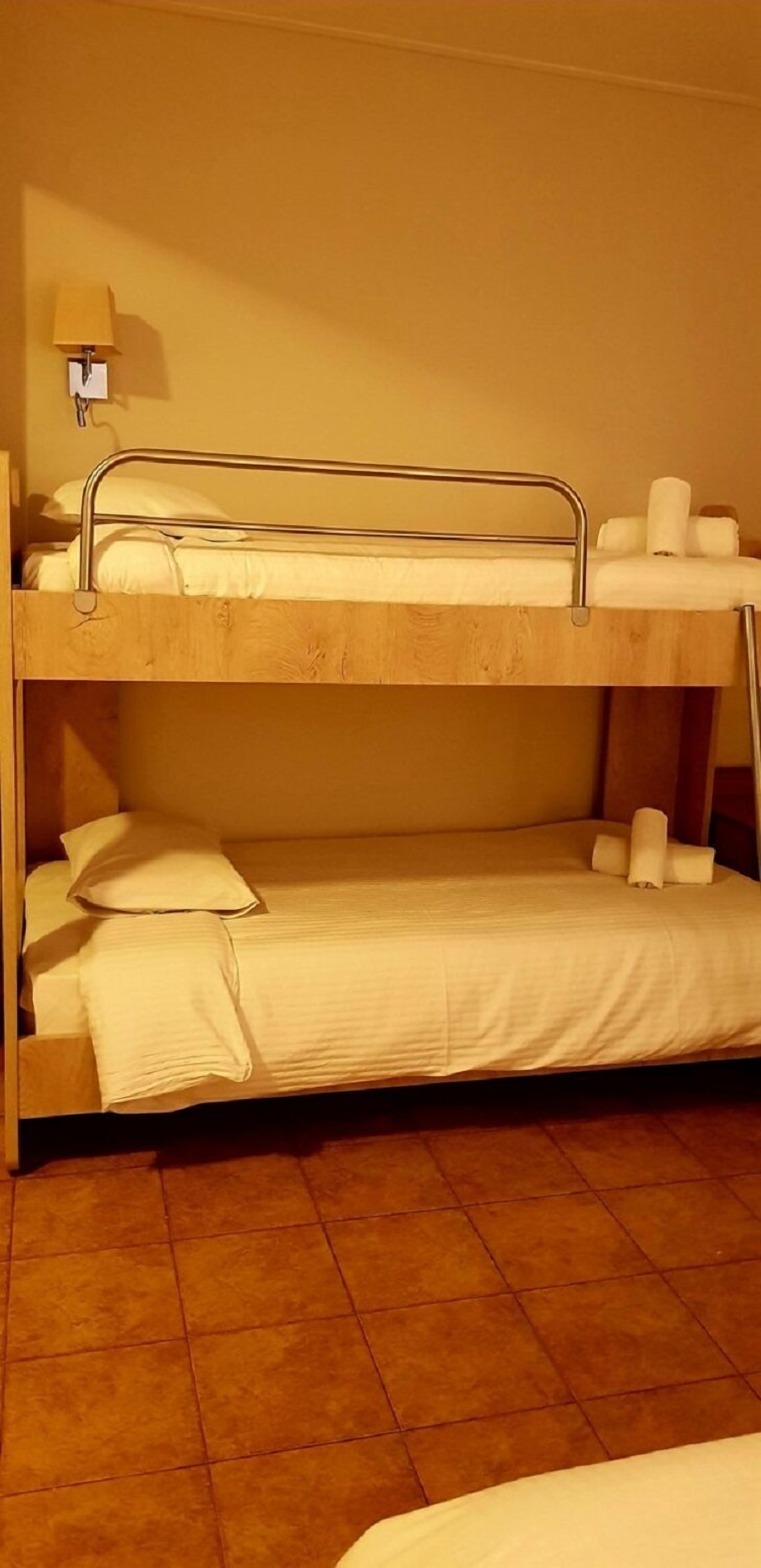 Uma cama beliche com dois níveis, cada um com travesseiros e toalhas enroladas.
