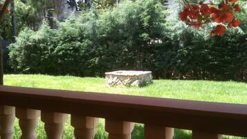 A stone bench in a lush garden with dense greenery and a flag in the background.