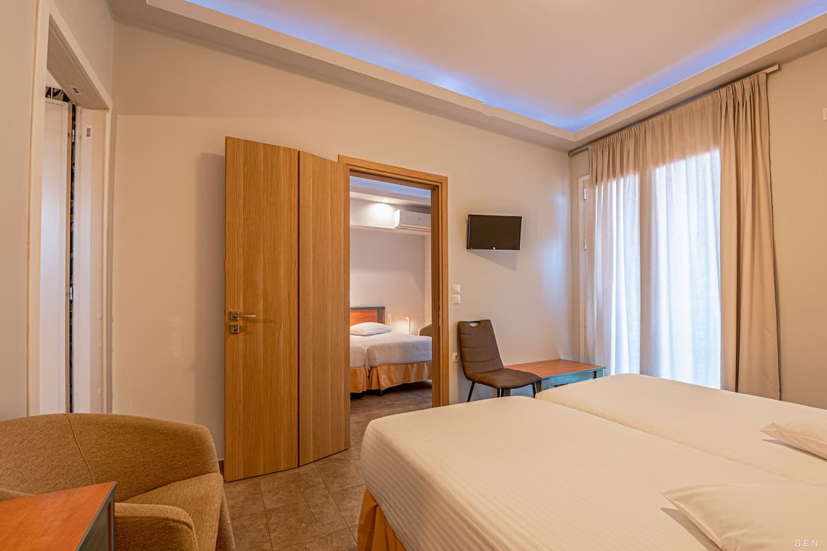 Quarto de hotel com uma cama grande, uma escrivaninha, uma cadeira e um guarda-roupa.