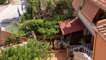 Ein Wohngebiet mit einem Haus, das ein rotes Ziegeldach, einen Balkon und einen Garten mit verschiedenen Pflanzen hat.